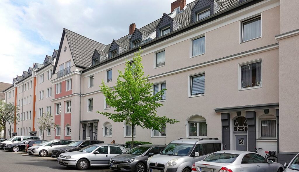 Häuserzeile mit bwb-Altbauten Rolandstraße, helle Fassaden, Baum, Autos nebeneinander davor